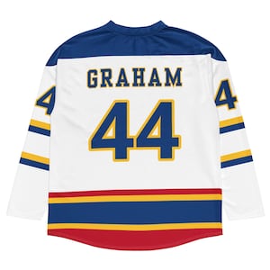 May include: White hockey jersey with blue and gold accents. The jersey features the name "GRAHAM" above the number "44" in blue and gold. The sleeves have blue and gold stripes, and the number "4" is on each sleeve.