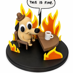 May include: A figurine depicting a cartoon dog sitting in a chair at a table with a coffee cup, surrounded by flames. A speech bubble above the dog reads "THIS IS FINE." The base is black, and the flames are yellow and orange.