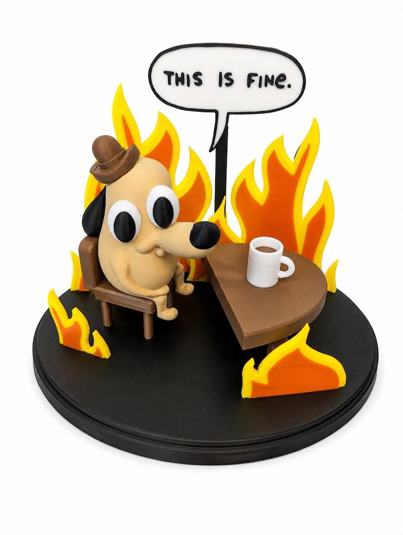May include: A figurine depicting a cartoon dog sitting in a chair at a table with a coffee cup, surrounded by flames. A speech bubble above the dog reads "THIS IS FINE." The base is black, and the flames are yellow and orange.