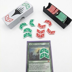 以下が含まれることがあります： ゲームアクセサリーのセット。黒いシンボルが付いた灰色のトークンホルダー、赤と緑のトークンが入った黒いトレイ、+1/-1のシンボルが付いたルーズな赤と緑のトークン。テキスト付きのカードも含まれています。