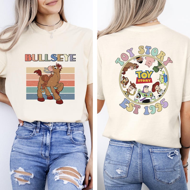 Może przedstawiać: Kremowa koszulka z grafiką Bullseye i napisem "BULLSEYE". Tył koszulki zdobi okrągły wz&oacute;r z napisem "TOY STORY EST 1995" i postaciami z Toy Story.