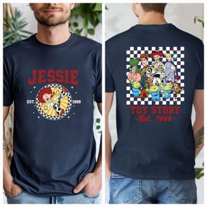 Puede incluir: Camiseta azul marino con un gr&aacute;fico frontal de Jessie de Toy Story, el texto "JESSIE" y "EST. 1999". La parte trasera muestra un gr&aacute;fico grupal de Toy Story y el texto "TOY STORY - Est. 1999".
