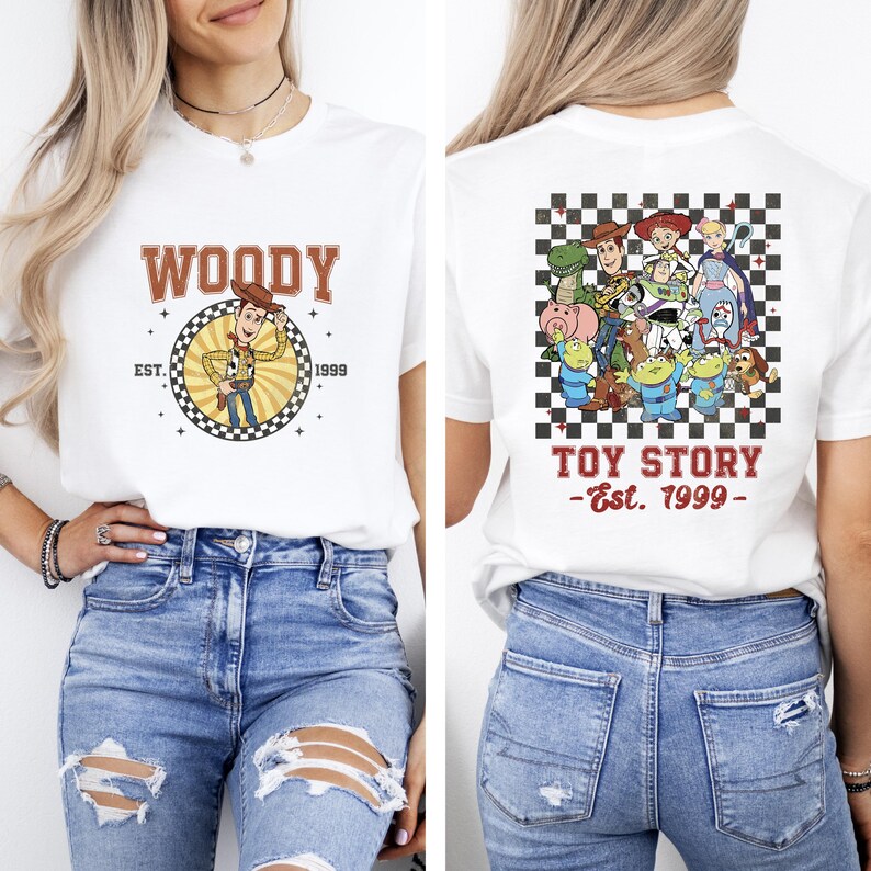 K&ouml;nnte beinhalten: Wei&szlig;es T-Shirt mit einem Woody-Motiv und dem Text "WOODY" und "EST. 1999" auf der Vorderseite. Auf der R&uuml;ckseite des Shirts sind Toy Story-Charaktere und der Text "TOY STORY - Est. 1999" zu sehen.