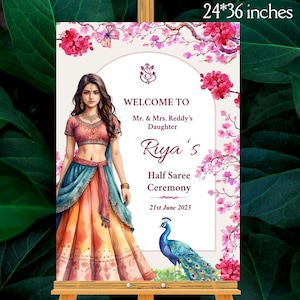 Puede incluir: Un letrero decorativo, de 61 x 91 cm, para una ceremonia de Half Saree. El letrero presenta una ilustración de una mujer con vestimenta tradicional, un pavo real y detalles florales. El texto incluye "Welcome to Riya's Half Saree Ceremony, 21st June 2023."