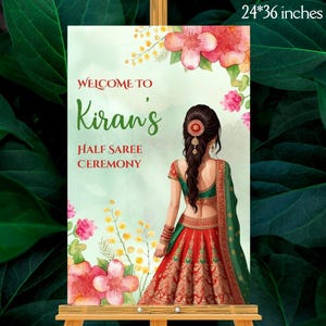 Puede incluir: Un letrero de bienvenida de 61 x 91 cm para una ceremonia de medio sari. El letrero presenta el texto "Welcome to Kiran's" en escritura verde, con detalles florales. Una ilustración de una mujer con un sari rojo y verde está en el lado derecho.