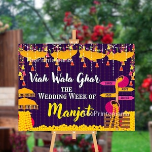Könnte beinhalten: Ein dekoratives Schild auf einer Staffelei mit dem Text "Viah Wala Ghar" und "The Wedding Week of Manjot". Das Schild ist lila mit gelben und rosa Akzenten, einschließlich Schirmen und Richtungspfeilen für Tanz, Essen, Fahrgeschäfte und Selfies.