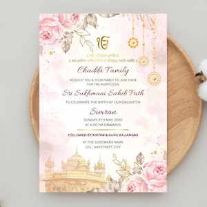 May include: A wedding invitation with a soft pink and gold floral design. The text includes the family name, event details, and a watercolor illustration of a temple. The invitation is on a wooden plate with cotton and dried flowers.