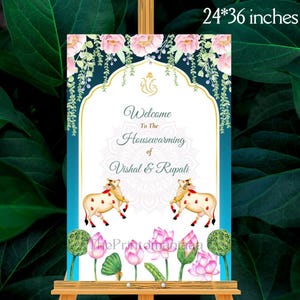 May include: A welcome sign for a housewarming, measuring 24x36 inches. The sign features a teal and gold arch design with floral accents and the text "Welcome To The Housewarming of Vishal & Rupali." Two cow illustrations are at the bottom.