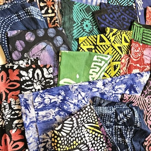 May include: A collection of colorful, patterned fabric pieces. The fabrics display a variety of designs, including geometric shapes, floral patterns, and tie-dye effects. Colors range from deep blues and blacks to vibrant greens, yellows, and reds. The textiles are neatly folded.