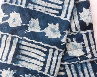 Könnte beinhalten: Indigostoff mit weißem, abstraktem Muster. Das Design zeigt rechteckige und unregelmäßige Formen mit einem Spritzeffekt. Der Stoff ist gefaltet und zeigt die Wiederholung und Textur des Musters. Die Gesamtästhetik ist künstlerisch und textilorientiert.