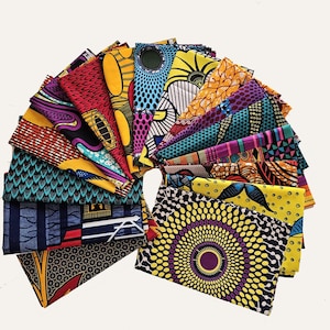 May include: A collection of vibrantly patterned African wax print fabrics, fanned out to display the variety of designs. The fabrics feature bold colors and geometric and floral motifs. The arrangement showcases the diverse patterns and color palettes available.