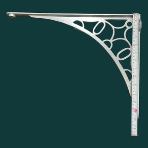 K&ouml;nnte beinhalten: Silberfarbene Metall-Winkelkonsole mit einem verzierten, durchbrochenen Design. Die L-f&ouml;rmige Halterung hat eine gebogene St&uuml;tze mit ovalen und kreisf&ouml;rmigen Aussparungen. Die L&auml;nge betr&auml;gt ca. 35,5 cm, wie durch ein Lineal angezeigt.