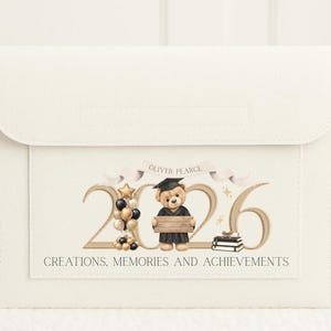 May include: Cream-coloured graduation keepsake box with a flap. The front has a graphic with the year 2026, a teddy bear in a graduation gown, balloons, and the text "Creations, Memories and Achievements."