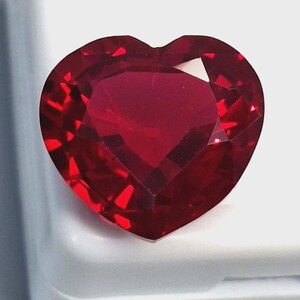 Può includere: Una gemma sfaccettata a forma di cuore, di un colore rosso intenso e ricco. La gemma ha molteplici sfaccettature che riflettono la luce, creando un effetto scintillante. La forma generale è un cuore perfetto.