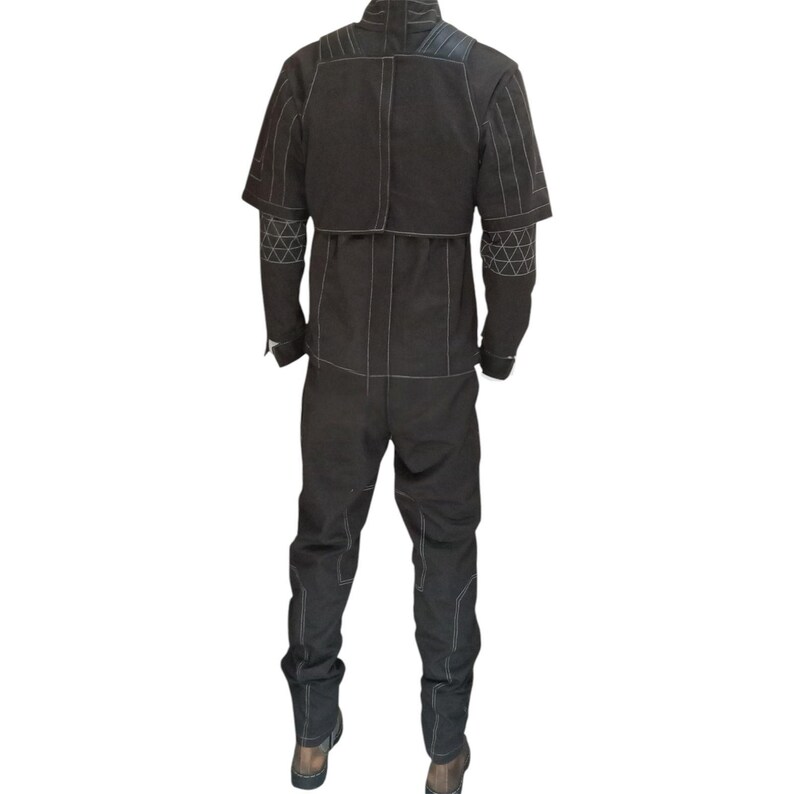 May include: Black jumpsuit with white stitching details. The suit features a high collar, short sleeves, and long pants. Geometric patterns are visible on the sleeves. The suit appears to be made of a durable material.