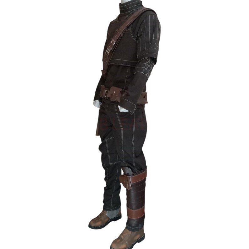 May include: A brown costume with white stitching, featuring a high-collared jacket, pants, and a belt with pouches. The outfit includes a shoulder strap and brown leather boots. The costume is displayed on a mannequin.