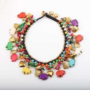 May include: A charm bracelet featuring a black braided cord base adorned with numerous colorful beads, gold-toned metal hearts, small metallic bells, and various animal-shaped charms in shades of red, green, blue, yellow, and purple.