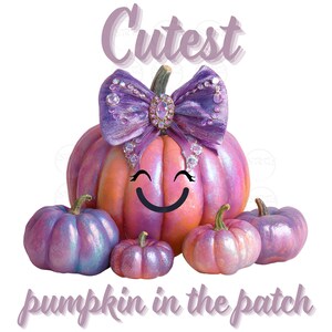 May include: A whimsical illustration of a pumpkin family. The largest pumpkin is pink and orange with a purple bow and a smiling face. Surrounding it are smaller pumpkins in shades of pink and purple. Text reads "Cutest pumpkin in the patch."