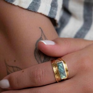 May include: A gold ring with a rectangular, light blue gemstone. The ring has a layered band design. The text "Thegemshub777" is visible in the background.