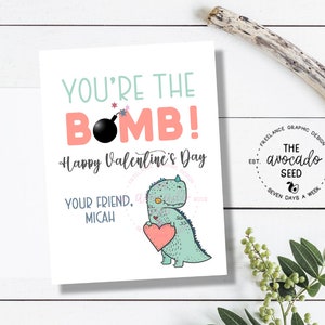 Puede incluir: Una tarjeta de San Valentín con un dinosaurio verde sosteniendo un corazón rosa. La tarjeta dice "You're the Bomb! Happy Valentine's Day. Your Friend, Micah."