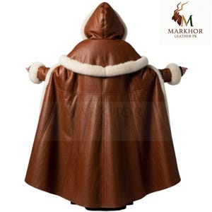 May include: A brown leather hooded cape with white fur trim around the hood and cuffs. The cape is made of a smooth, dark brown leather and has a flowing design. The back view shows the cape's full length and details.