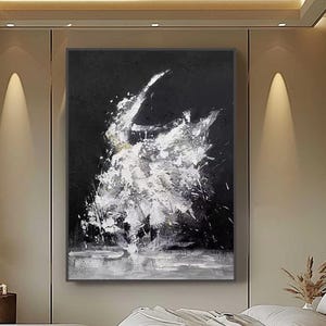 May include: Abstract black and white painting with dynamic brushstrokes, mounted above a bed in a modern bedroom. The artwork features a central burst of white against a dark background, creating a striking contrast. The room includes a bed, ottomans, and a large window.