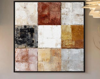 Könnte beinhalten: Abstrakte quadratische Kunst mit schwarzem Rahmen. Das Gemälde zeigt ein Raster aus strukturierten Quadraten in verschiedenen Farben, darunter Weiß, Schwarz, Rot und Gold. Das Kunstwerk wird in einem gut beleuchteten Raum ausgestellt, was auf ein modernes Interior Design hindeutet.
