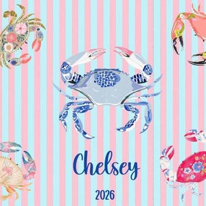 May include: A patterned design featuring five crabs in various colors and patterns, set against a background of pink and blue vertical stripes. The name "Chelsey" and the number "2026" are written in blue script.
