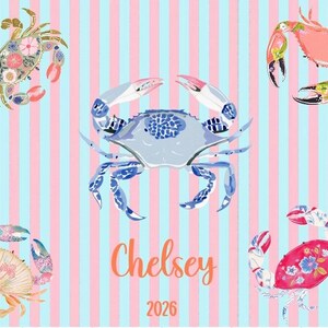 May include: A whimsical design featuring five illustrated crabs in various colors and patterns against a striped background of light blue and pink. The name "Chelsey" and the number "2026" are written in orange script.