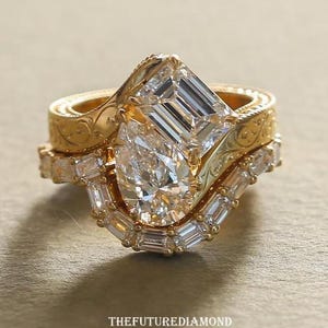 Op de afbeelding: Een set van drie gouden ringen met ingewikkelde details. De ringen hebben een peervormige diamant, een smaragdgeslepen diamant en verschillende kleinere diamanten. De ringen zijn op elkaar gestapeld, wat een unieke en elegante uitstraling cre&euml;ert. De tekst "THEFUTUREDIAMOND" staat onderaan.