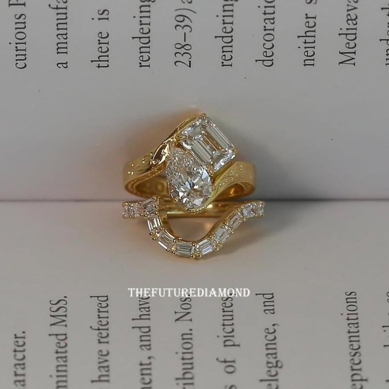 Op de afbeelding: Drie gouden ringen met diamantaccenten. De bovenste ring heeft een peervormige diamant en een smaragdgeslepen diamant. De middelste ring heeft een gebogen ontwerp met kleine diamanten. De ringen liggen op een wit oppervlak met tekst.