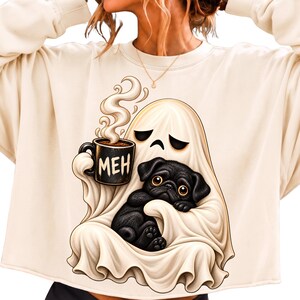 Könnte beinhalten: Ein cremefarbenes Sweatshirt mit Rundhalsausschnitt und einer Grafik eines weißen Geistes, der eine schwarze Tasse mit der Aufschrift MEH und aufsteigendem Dampf hält, während er einen kleinen schwarzen Mops-Welpen im Arm hält.