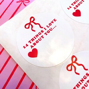 May include: Three white round stickers with red text and a red bow. The text on the stickers reads "14 things I love about you..." and a red heart is below the text.