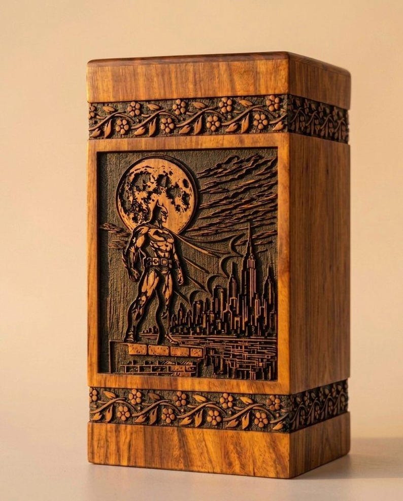 May include: A wooden box with a carved Batman scene. The artwork depicts Batman standing in front of a cityscape with a full moon. The box has floral carvings around the top and bottom.