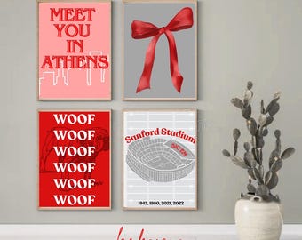May include: Four framed art prints with red and gray designs. One print says "Meet You In Athens", another features a red bow, a third says "Woof" repeatedly, and the last shows a stadium with the text "Sanford Stadium".