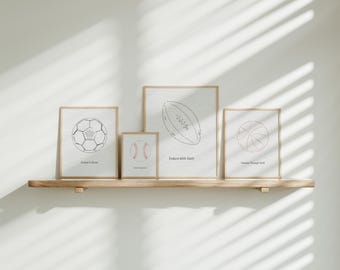 May include: Four framed prints with black and white line drawings of different sports balls. The prints are on a wooden shelf against a white wall. The text on the prints reads "United in Christ", "Never Change Who You Are", "Endure with Faith", and "Navigate Through Faith".
