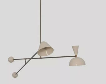 Pode incluir: Luminária de teto moderna e minimalista com acabamento em bronze e abajures em forma de cone e cúpula em branco sujo. A luminária tem um design linear com três detalhes esféricos e uma haste central.