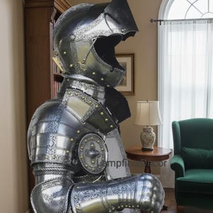 May include: A full suit of medieval armor, crafted from polished metal with intricate etched designs and brass accents. The helmet features a visor, and the armor includes articulated limbs and a chest plate. The armor is displayed indoors.