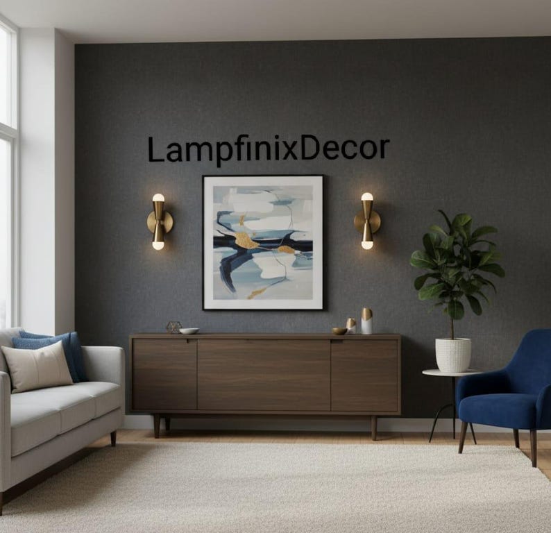 May include: A contemporary living room scene featuring a grey sofa, a dark wood cabinet, and a blue armchair. The wall displays a framed abstract painting and two gold sconces. The text "LampfinixDecor" is visible on the wall.