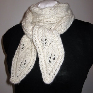 May include: A white knitted scarf with a delicate leaf pattern. The scarf is draped over a black mannequin.