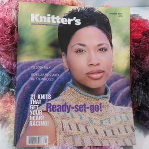 May include: The cover of "Knitter's" magazine, Spring 2003, features a woman wearing a knitted top. The magazine's title is in white letters on a green background. Text includes "Pillow Talk," "21 Knits," and "Ready-set-go!" The background is a purple and brown pattern.
