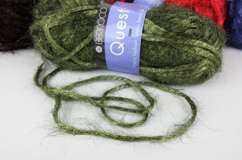 May include: A skein of green yarn with a metallic sheen. The yarn is labelled "Quest" and "Berroco".