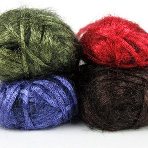 May include: Four balls of yarn stacked on top of each other. The top ball is red, the next is brown, the next is blue, and the bottom ball is green.