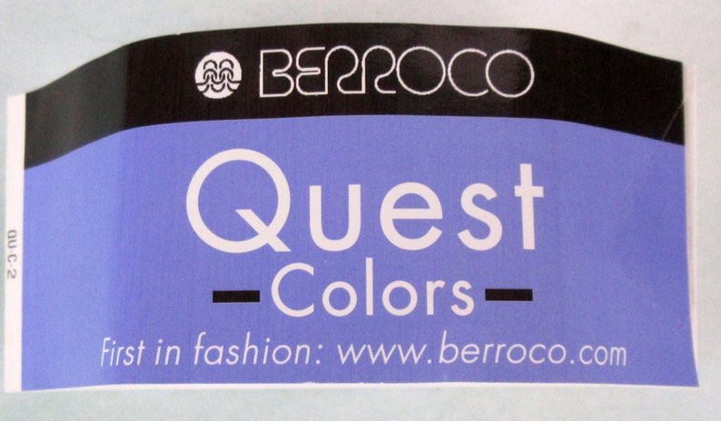 May include: A blue and black label with white text that reads "Quest - Colors - first in fashion: www.berroco.com". The label also features a logo with a stylized wave design and the word "Berroco".