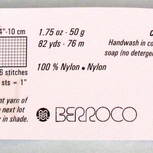 May include: A white label with black text and a logo for Berroco yarn. The label includes information about the yarn, such as the fibre content, weight, yardage, and care instructions. The label also includes a gauge swatch and needle size recommendations.