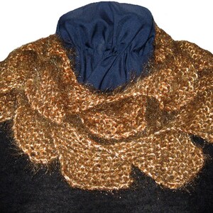 May include: A gold knitted scarf with a fluffy texture. The scarf is draped over a black mannequin.