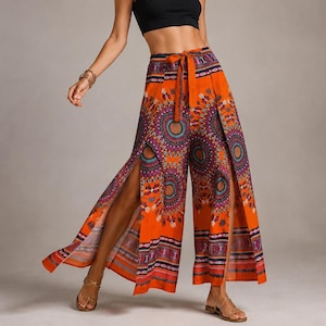 May include: A black sleeveless crop top paired with high-waisted orange wide-leg pants featuring a vibrant, multicolored mandala-inspired circular pattern, a tie-waist detail, and dramatic side slits that extend from the hem to the mid-thigh.