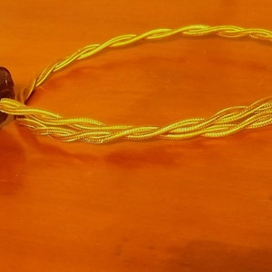 May include: A black electrical plug with a yellow and gold braided cord.