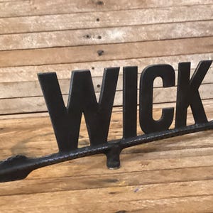 Weathervane arrow, WICK in cast aluminum with worn black paint. Old farm equipment, wind direction roof equipment. Wind spinner.