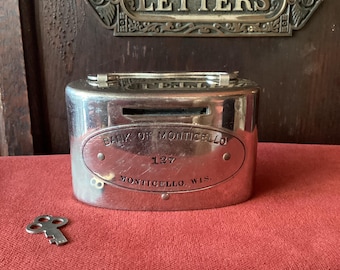 Oval chrome bank from Monticello Wisconsin. Bright and shiny chromed oval bank with key. Working repaired lock, coin slot Bank of Monticello
